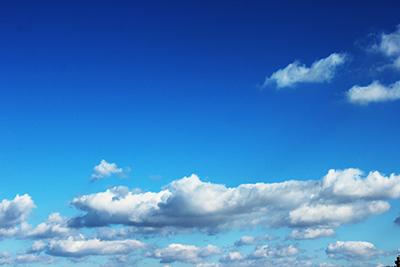 Valkoisia ja vaaleanharmaita pilviä sinisellä taivaalla.